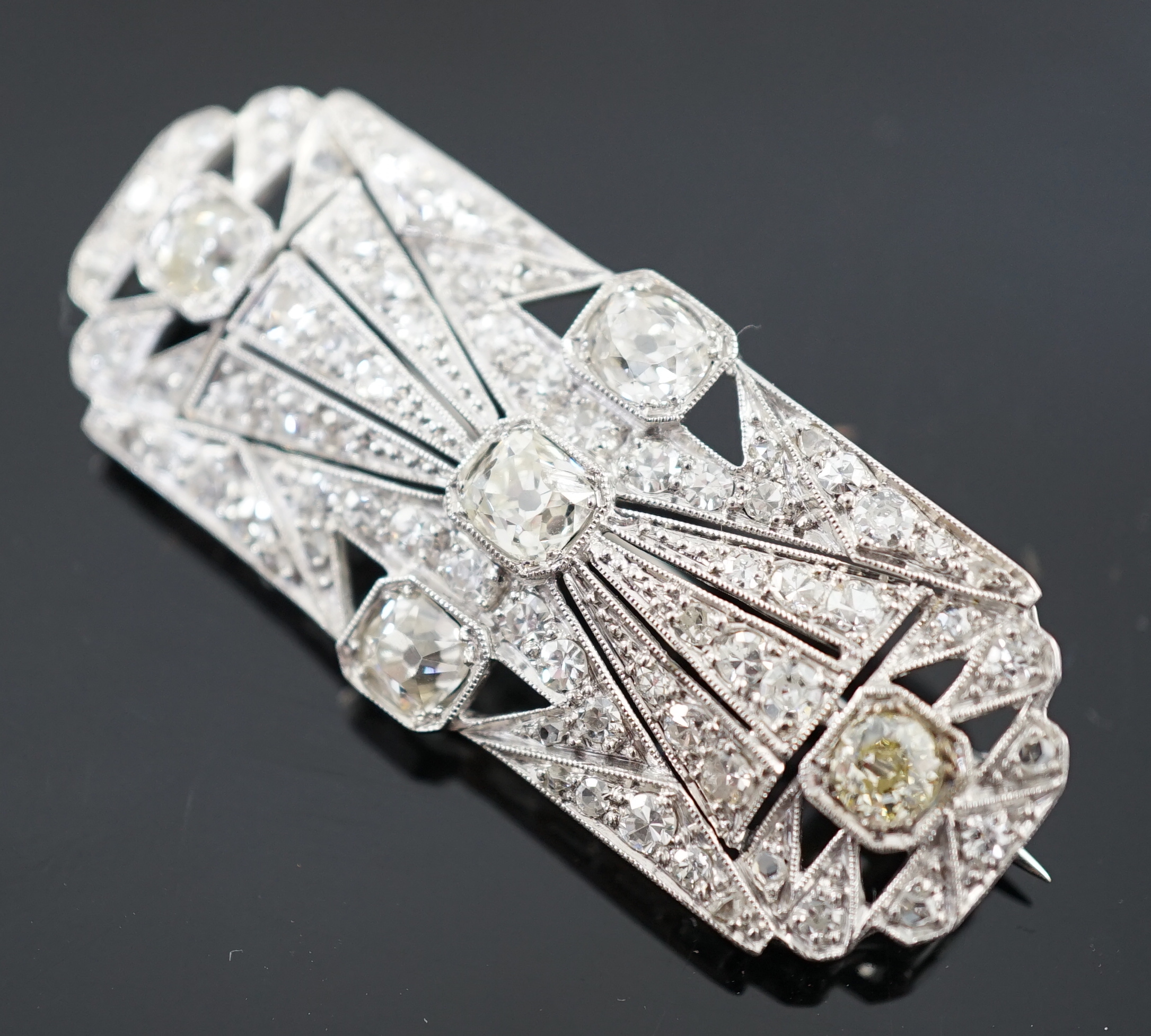 An Art Deco pierced platinum and millegrain set diamond cluster shaped rectangular brooch